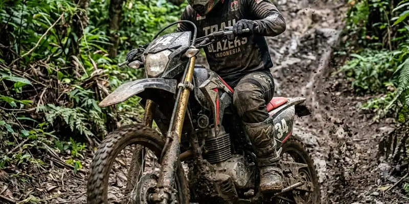 Seseorang mengendarai motor trail melintasi jalur sempit menanjak di dalam hutan